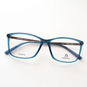 Könnte beinhalten: Blaue Kunststoff-Brille mit schwarzem Metallsteg und Bügeln. Die Bügel sind mit "R 5314  ø 130 CE" und "R RODENSTOCK" beschriftet.