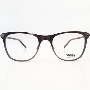Könnte beinhalten: Eine Brille aus schwarzem Metall mit klaren Gläsern. Der Markenname "rocco by rodenstock" ist auf dem rechten Bügel aufgedruckt.