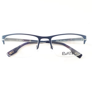 Könnte beinhalten: Marineblaue EVATIK-Brille mit rechteckigem Rahmen und Halbrand-Design. Die Bügel haben ein Muster und der Markenname ist auf dem Glas sichtbar. Die Brille ist vor einem weißen Hintergrund platziert.