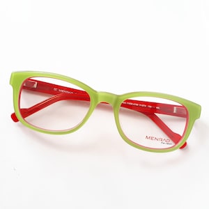 Könnte beinhalten: Grün-rote Brille mit rechteckigem Rahmen. Die Brille hat einen hellgrünen Rahmen mit roten Bügeln und Innenrahmen. Der Markenname "MENRAD" ist auf dem rechten Glas sichtbar.
