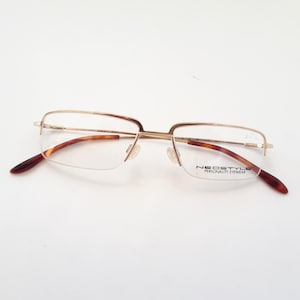 Könnte beinhalten: Goldfarbene Metallbrille mit klaren Gläsern und braunen Schildpattbügeln. Der Markenname "NEOSTYLE PERSONALITY EYEWEAR" ist auf dem rechten Glas aufgedruckt.