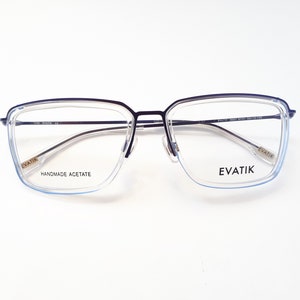 Peut inclure: Lunettes de vue avec monture en métal noir et verres en acétate transparent. Les verres ont une bordure bleu clair. Le nom de la marque "EVATIK" est imprimé sur les branches et les mots "HANDMADE ACETATE" sont imprimés sur le verre gauche.