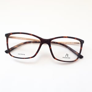 Könnte beinhalten: Schildpatt-Brille mit goldenen Akzenten und klaren Gläsern. Der Markenname "RODENSTOCK" ist auf dem rechten Bügel aufgedruckt.