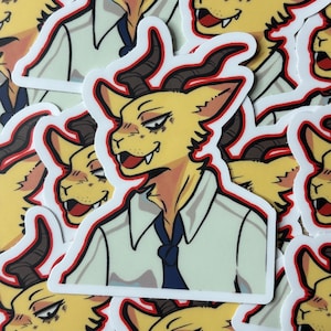 Puede incluir: Una pila de pegatinas con un personaje de dibujos animados con pelaje amarillo, cuernos y una camisa blanca con una corbata azul. El personaje tiene una expresión traviesa y mira hacia la derecha. Las pegatinas tienen un borde rojo.