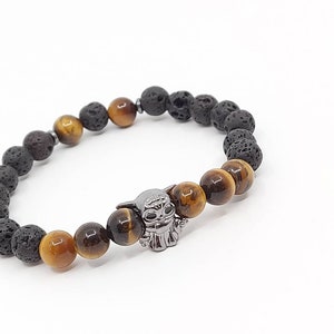 Peut inclure: Bracelet en perles de roche volcanique noire et d'œil de tigre avec un charme argenté représentant un personnage de dessin animé.