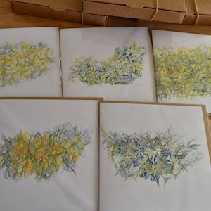 May include: Five blank greeting cards featuring abstract watercolour designs in shades of yellow, green, and blue. The cards are all the same size and are arranged in a row.
