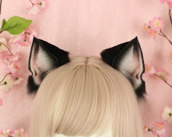 May include: A pair of faux fur cat ears featuring black outer edges and white inner fur with pinkish accents. The ears are positioned atop a head with straight, light blonde hair, showcasing a realistic texture and pointed triangular shape.
