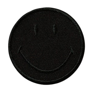 Könnte beinhalten: Schwarzer gestickter Smiley-Patch. Der Patch ist rund und hat einen schwarzen Hintergrund mit einem weißen Umriss.