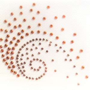 May include: A white background with a spiral design made of small, orange rhinestones.