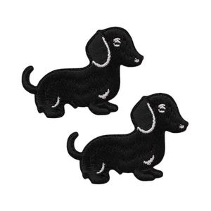May include: Two black dachshund dog patches with white embroidered details. The patches feature a side profile of the dog with a curved tail and floppy ear. These patches are ideal for adding to clothing or accessories.