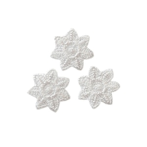 May include: Three white embroidered flower appliques. Each applique is a six-pointed star shape with a raised, textured design.