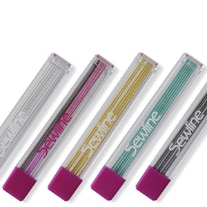 May include: Five clear plastic cases of Sewline sewing machine needles. Each case has a different color of needles: white, pink, gold, green, and gray. The cases are all pink.