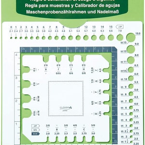 May include: A green and white plastic swatch ruler and needle gauge with markings in millimeters and inches. The gauge has a square grid with circles for measuring needle sizes in US and Japanese sizes. The ruler has markings for measuring in centimeters and inches.