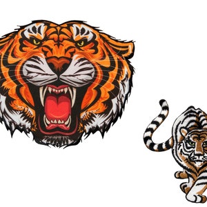 Könnte beinhalten: Zwei gestickte Tiger-Patches. Der erste Patch ist eine Nahaufnahme eines Tigergesichts mit offenem Maul und scharfen Zähnen. Der zweite Patch ist ein ganzer Tiger mit einem eingerollten Schwanz.