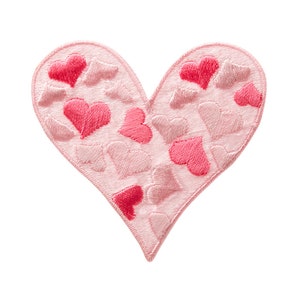 Puede incluir: Un parche de fieltro rosa en forma de corazón con un patrón de corazones más pequeños de color rosa y rojo.