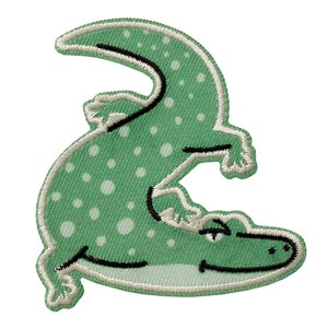 Op de afbeelding: Groene geborduurde patch van een cartoon alligator met witte stippen, liggend op zijn rug met zijn poten in de lucht.