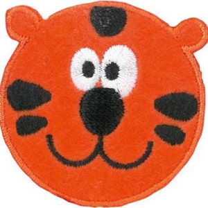 Könnte beinhalten: Orangefarbener, gestickter Aufnäher in Form eines Cartoon-Tigergesichts. Das Design umfasst große weiße Augen mit schwarzen Pupillen, eine schwarze Nase und schwarze Markierungen. Der Aufnäher hat eine runde Form mit einem gestickten Rand.