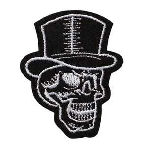 Könnte beinhalten: Schwarz-weiß gestickter Bügel-Patch mit einem Totenkopf, der einen Zylinder trägt. Der Schädel ist weiß umrandet und hat ein weißes Auge und Zähne.