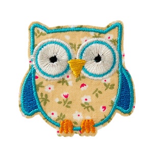 May include: A yellow fabric owl with blue wings and white eyes. The owl has a floral pattern and a yellow beak.