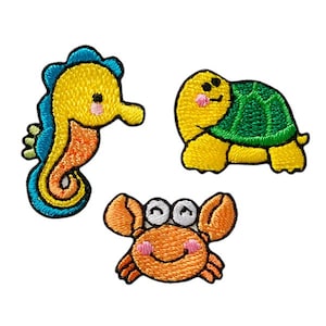 Könnte beinhalten: Drei aufgestickte Aufnäher mit Meeresbewohnern. Ein gelbes Seepferdchen mit blauen und orangen Akzenten, eine gelbe Schildkröte mit grünem Panzer und eine orangefarbene Krabbe mit lächelndem Gesicht. Ideal zum Dekorieren von Kleidung.