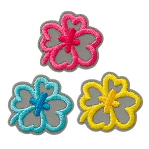 May include: Three embroidered iron-on patches in the shape of a four-leaf clover. The clovers are pink, blue, and yellow.