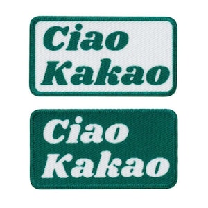 May include: Two rectangular patches with the text "Ciao Kakao" in a bold, green font. One patch has a white background, the other is green. Both patches have a green border and are likely embroidered.