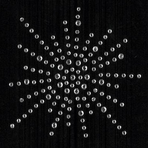 May include: A silver starburst design made of small, round rhinestones on a black background.