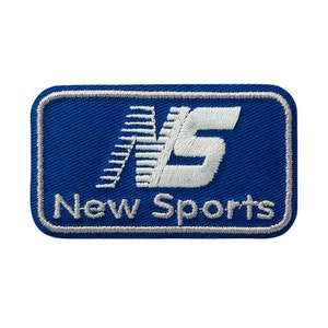 以下が含まれることがあります： 「New Sports」というテキストとスタイリッシュな「NS」ロゴが刺繍された青と白のパッチ