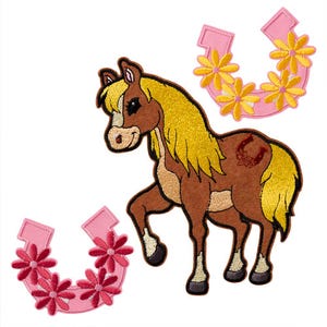 May include: A brown horse with a blonde mane and tail, standing on all four legs. The horse has a horseshoe on its flank. There are two pink horseshoes with yellow flowers on them.