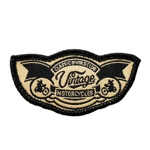 Può includere: Una toppa ricamata nera e marrone con il testo "Classic Bikers Club Vintage Motorcycles". La toppa presenta due motociclette stilizzate.
