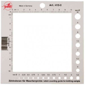 May include: A white plastic stitch counting guide with a grid and a ruler marked in centimeters and millimeters. The guide is labeled "Art.: 412-0" and "Zählrahmen für Maschenprobe / stitch counting guide for knitting sample".