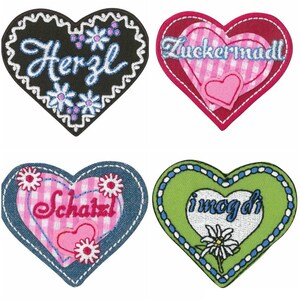 Pode incluir: Quatro patches de feltro bordados em forma de coração com diferentes designs e dizeres. O primeiro patch é preto com costuras brancas e diz "Herz" em itálico. O segundo patch é vermelho com xadrez branco e rosa e diz "Zuckermadel". O terceiro patch é azul com xadrez branco e rosa e diz "Schatzl". O quarto patch é verde com costuras brancas e azuis e diz "i mog di".