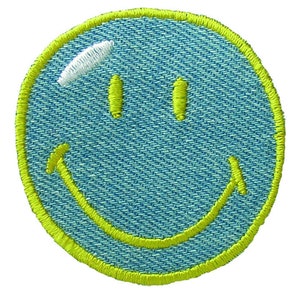Peut inclure: Un patch smiley bleu avec un contour jaune. Le patch est en jean et a une surface texturée.