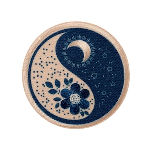 Könnte beinhalten: Runder, gestickter Aufnäher mit Yin-Yang-Motiv. Eine Hälfte ist marineblau mit Mond und Sternen, die andere beige mit floralem Design. Der Aufnäher hat einen beigen Rand.
