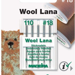 May include: A pack of Madeira Wool Lana embroidery needles, size 110/18. The pack is white with green text and a green logo. The needles are silver and are displayed in a clear plastic case.