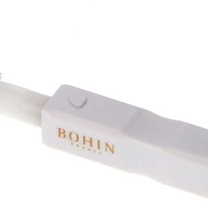 Puede incluir: Herramienta de plástico blanco con una punta de metal plateado y un botón negro. La herramienta está etiquetada como "BOHIN FRANCE".