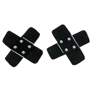 Puede incluir: Dos parches de tela negra en forma de venda con lunares blancos.