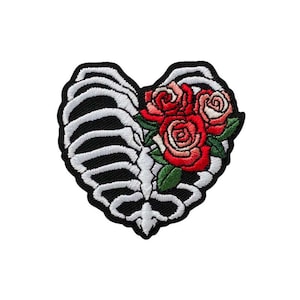May include: Embroidered patch in the shape of a heart, featuring a skeleton rib cage on the left and three red roses with green leaves on the right. The patch has a black border and is on a white background.