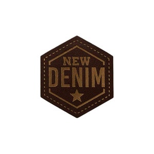 Könnte beinhalten: Ein braunes Leder-Patch mit einem goldenen Stern und dem Text "NEW DENIM" in goldenen Buchstaben.