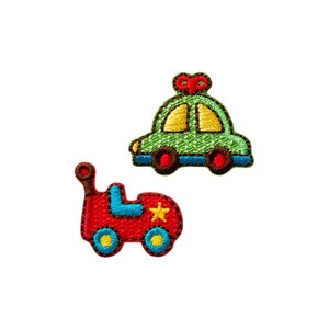 Op de afbeelding: Twee geborduurde strijkpatches met speelgoedauto's. Eén auto is groen met een rode strik bovenop en de andere is rood met een gele ster.