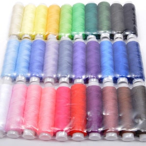 Peut inclure: Un ensemble de 48 bobines de fil de différentes couleurs, dont le blanc, le rose, le bleu, le vert, le jaune, le rouge, le violet, le marron et le gris. Les bobines sont disposées en rangées et emballées dans du plastique transparent.