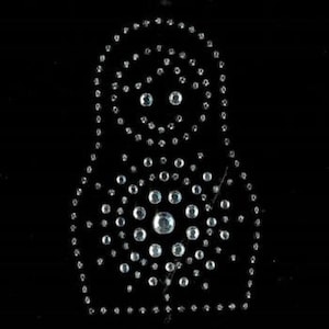 Puede incluir: Un fondo negro con un contorno blanco de una muñeca rusa hecha de diamantes de imitación.