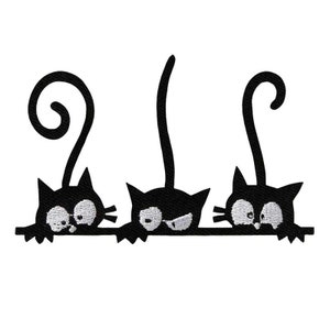 Può includere: Tre gatti neri con occhi bianchi che guardano da sopra una superficie. I gatti hanno le code arricciate e guardano in direzioni diverse.