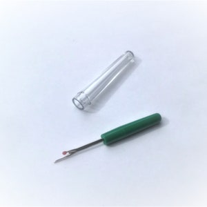 May include: A small, green thread cutter with a red tip and a clear plastic case.
