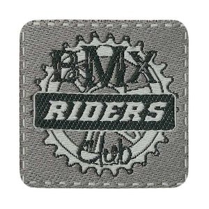 Könnte beinhalten: Ein grauer Stoff-Patch mit einem weißen Zahnrad-Design und dem Text "BMX RIDERS CLUB" in Schwarz.