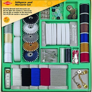 Op de afbeelding: Een groene plastic naaikit met verschillende naaigerei, waaronder garen, knopen, elastiek, naalden en spoeltjes. De kit is gelabeld "Nähgarn- und Mercerie-Set" en bevat de tekst "Sewing thread and mercerie set".