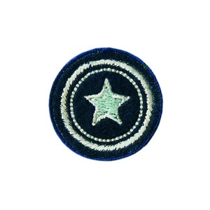 Könnte beinhalten: Ein blauer und weißer gestickter Aufnäher mit einem weißen Stern in der Mitte. Der Aufnäher ist rund und hat einen weißen Rand.