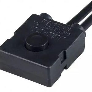 May include: A black electrical component with a round button on top and two black wires extending from the top. The component has text on the side. The item is likely used in electronics or appliances.