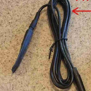 May include: Black push-to-talk (PTT) cable with a coiled design. The cable has a black connector on one end and a black PTT button on the other. The text "PTT" is visible in red.