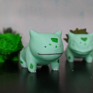 Puede incluir: Tres figuras impresas en 3D de color verde y blanco de un personaje de dibujos animados popular. Las figuras están en diferentes posiciones y tienen detalles verdes.
